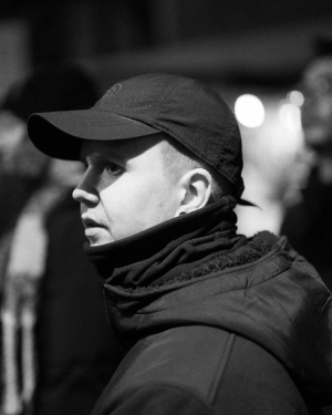 Techwear.Germany aka Janek in einem komplett schwarzen Techwear Outfit mit North Face Cap, Neck Gaiter und Uniqlo Fleece Jacke